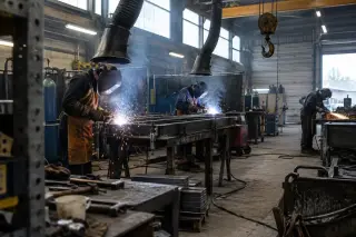 Soudeurs au travail sous des hottes d’aspiration dans un atelier de chaudronnerie